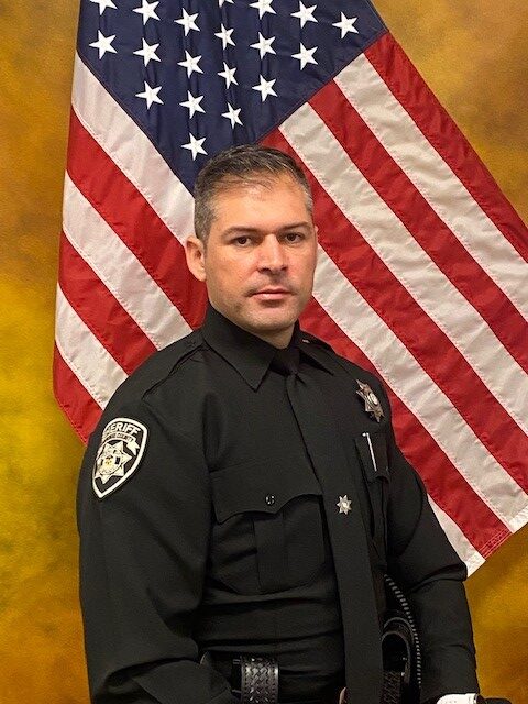 Cherokee County deputy Andre Marzola in uniform before an American flag