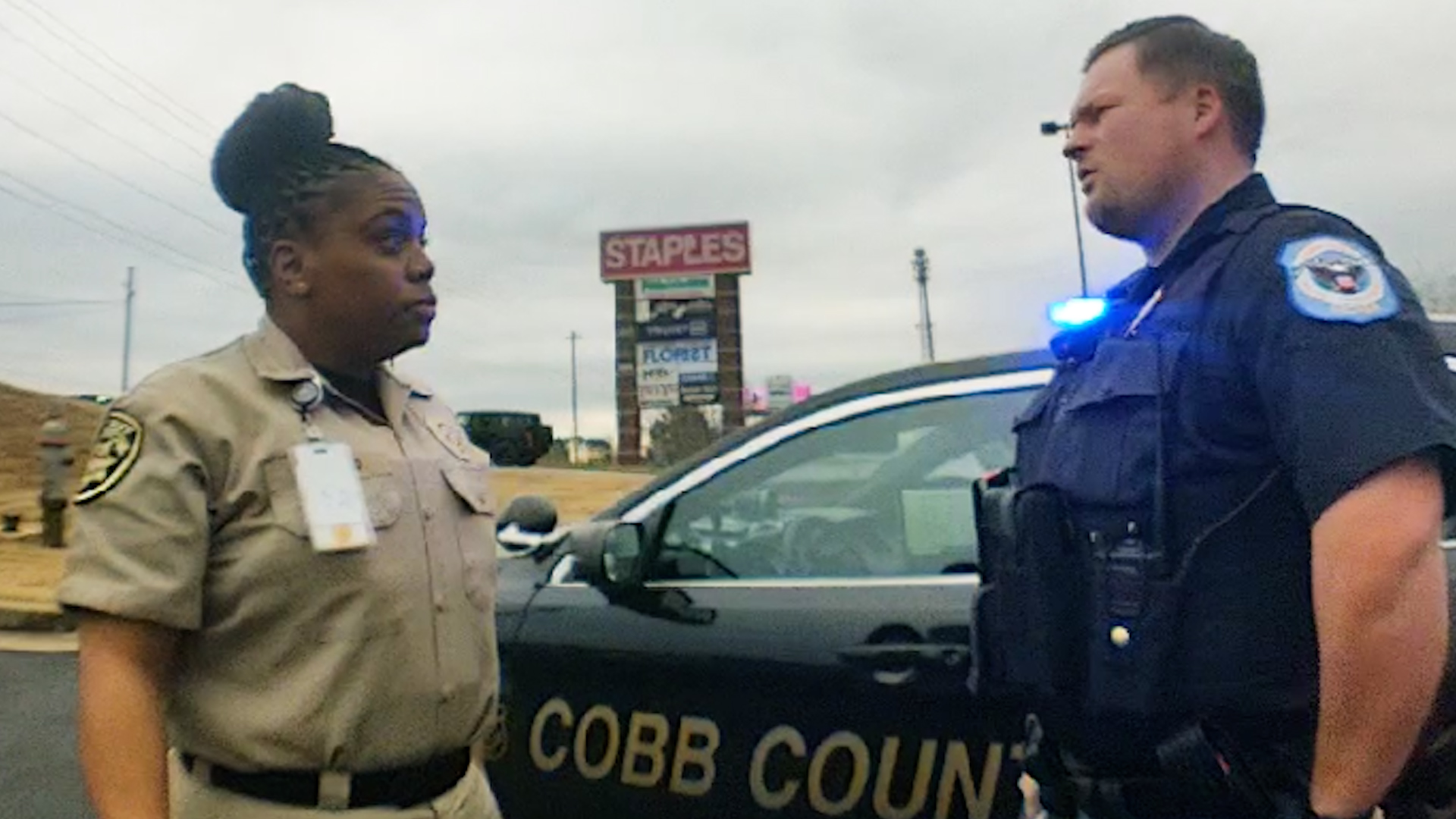 Body camera still 1: jailer speaking with officer near Cobb County police vehicle
